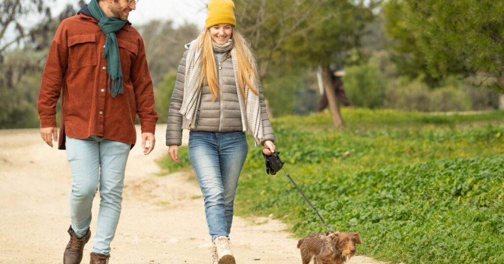 young couple walking their dachshund dog outside in the cold weather