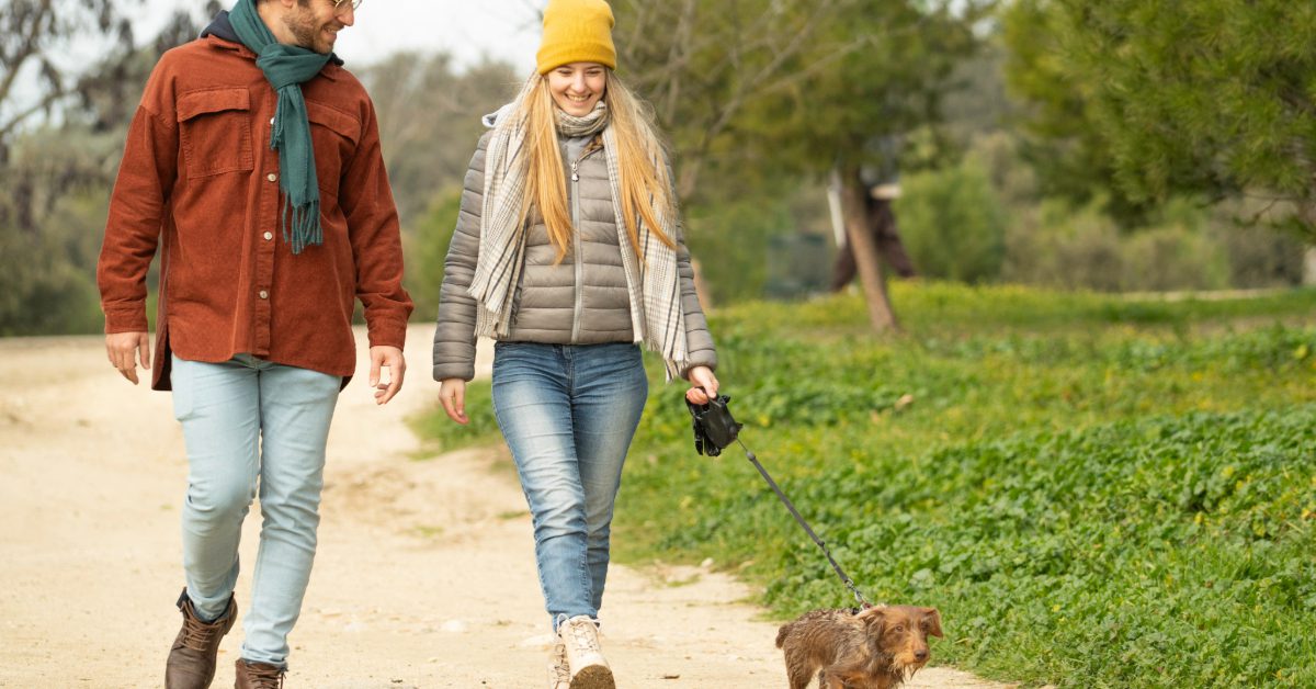 young couple walking their dachshund dog outside in the cold weather